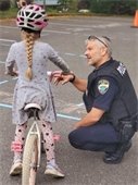 Child on bike being helped by police lieutenant